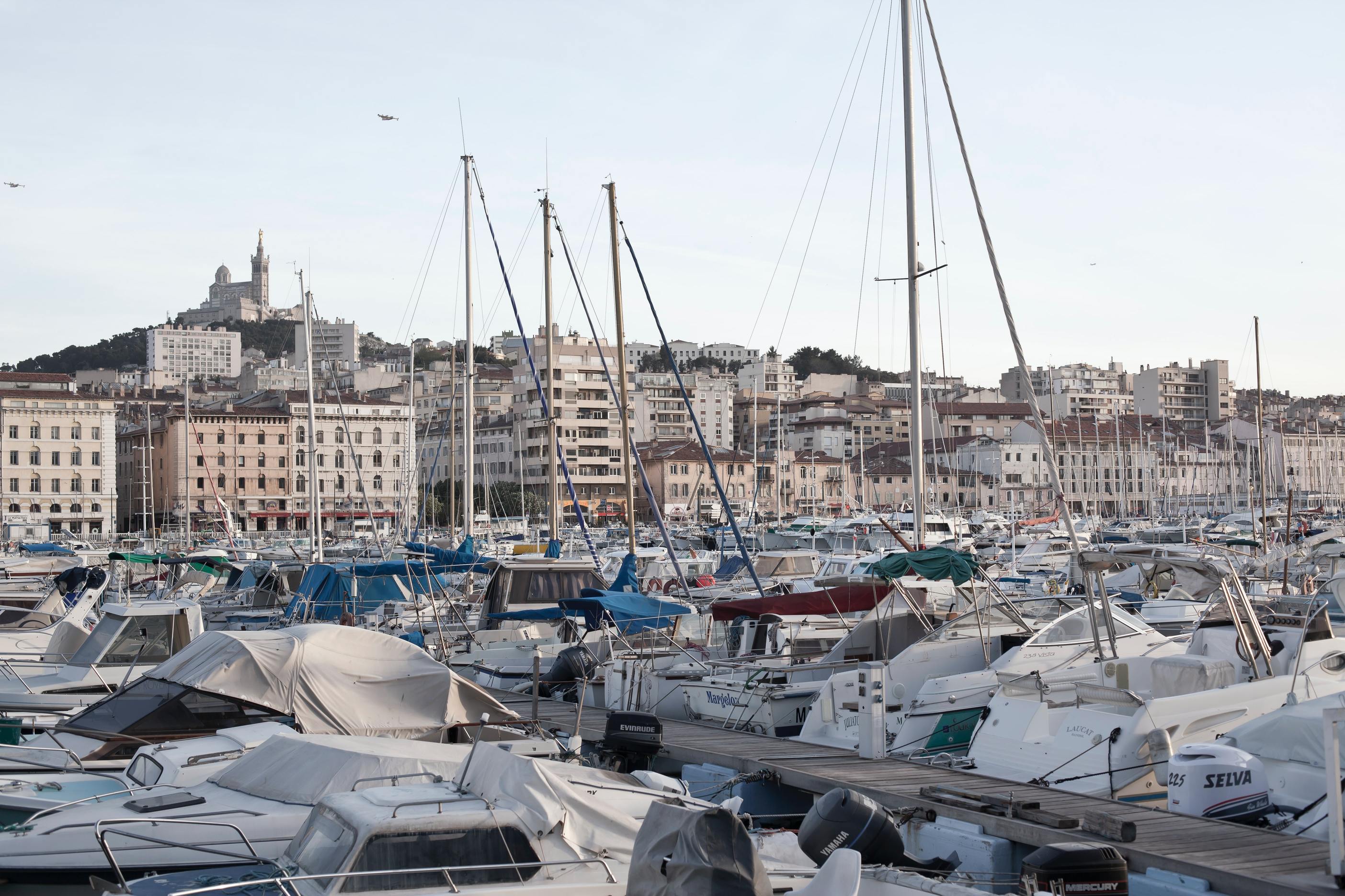 Vue du Vieux Port : bateaux, mâts, immeubles, basilique Notre-Dame-de-la-Garde sur sa colline 